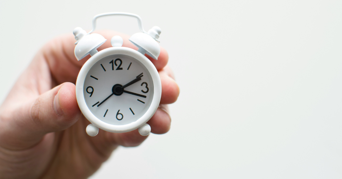 person holding white mini bell alarmclock